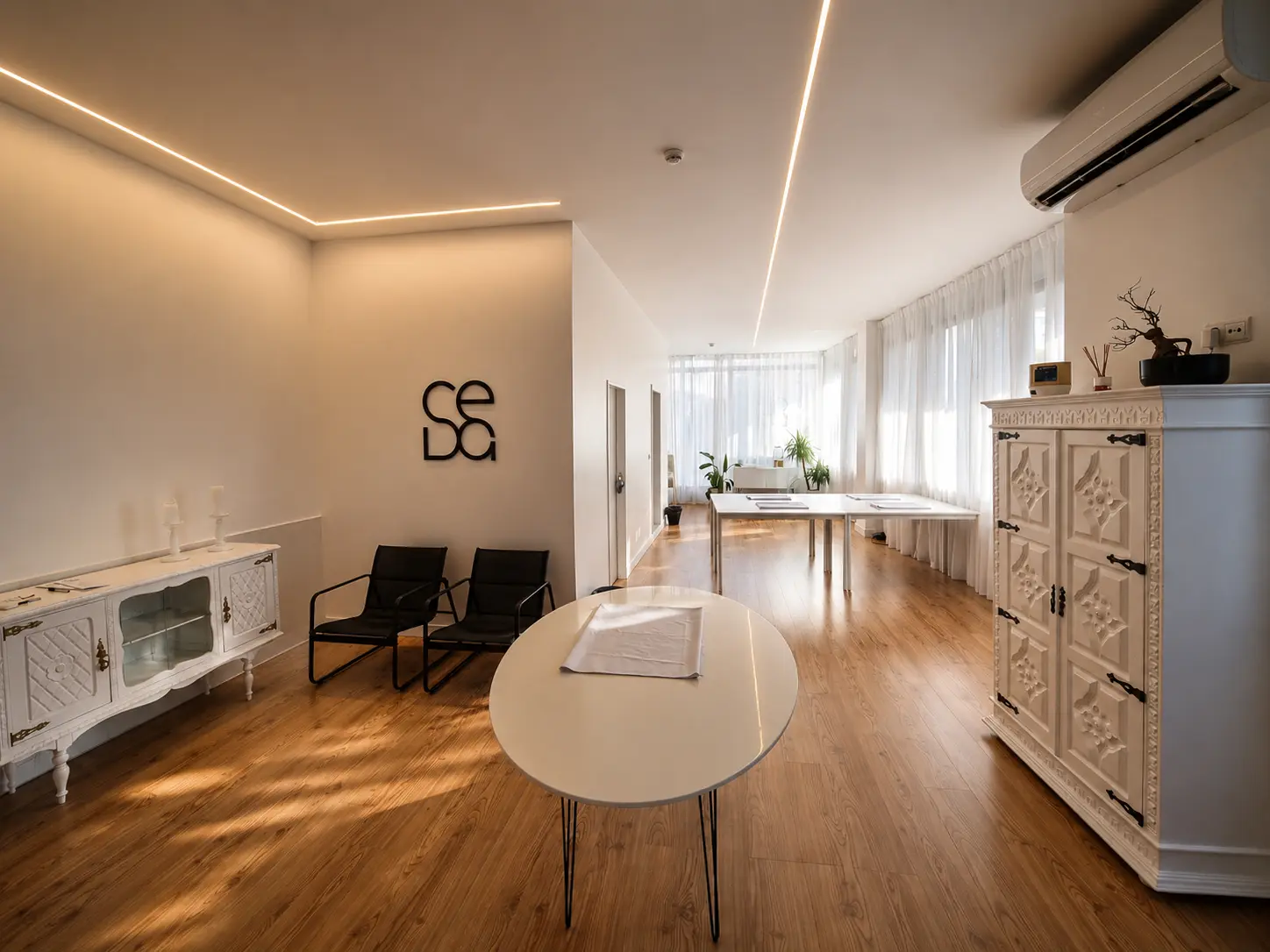 Interior da Seda Eventos visto da entrada, com aparadores brancos, cadeiras e mesa de apoio